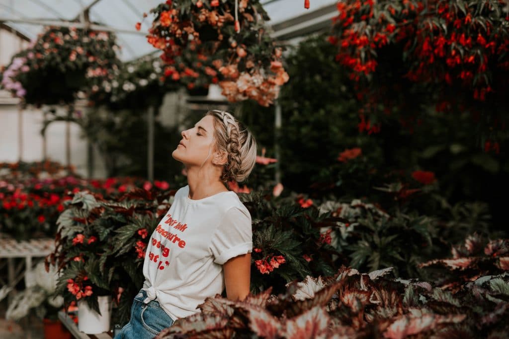 A girl closing her eyes with flowers around her